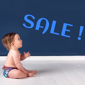 baby in wasbare zwemluier kijkt naar het woord sale